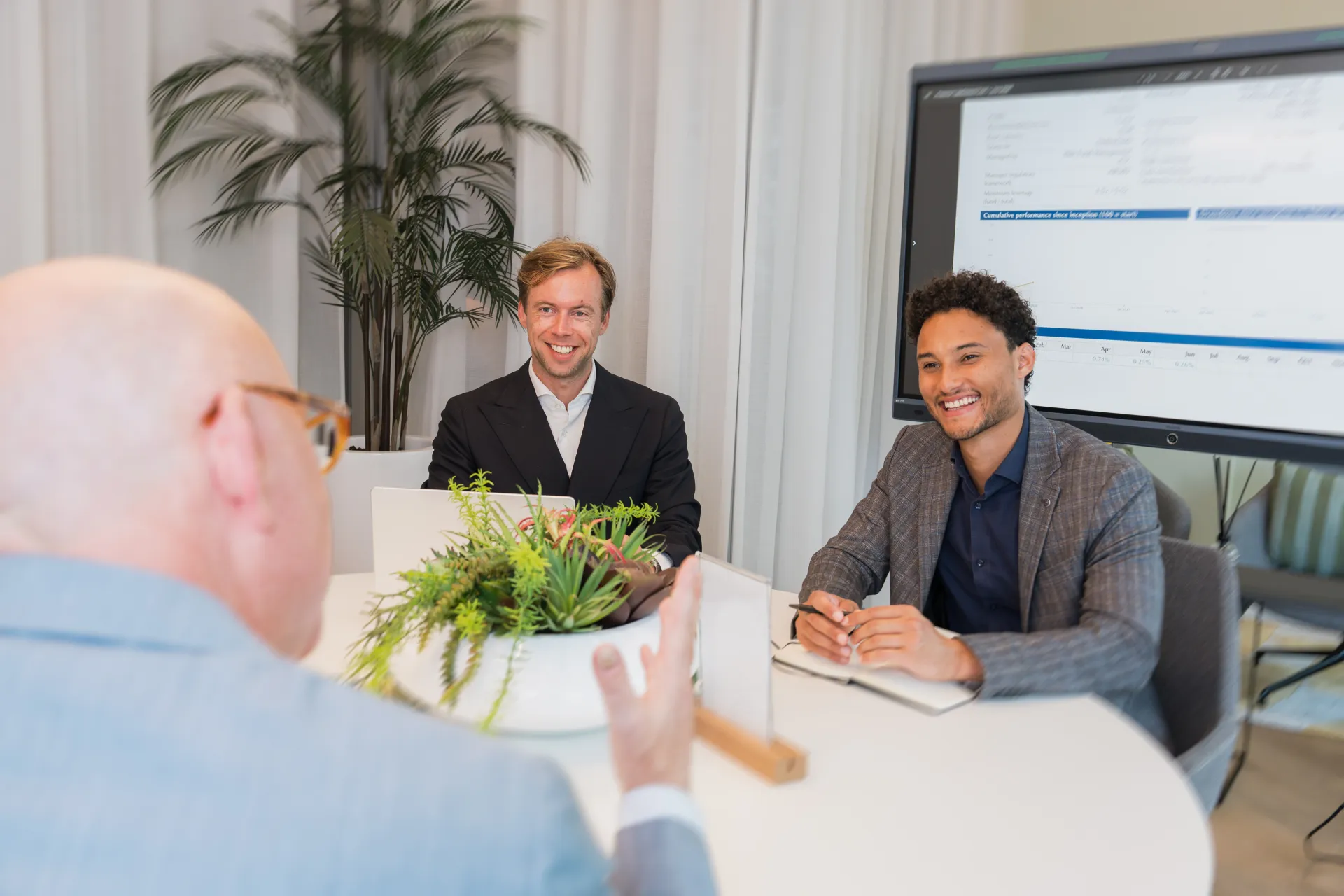 Overleg aan tafel op het kantoor van BOTS Capital, met een lachend teamlid